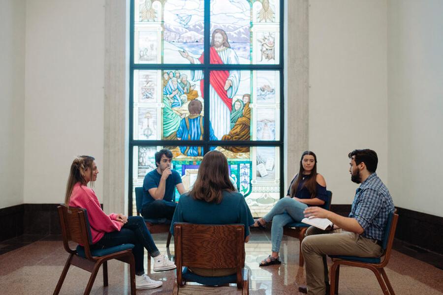 Ministry students sit in a circle and study the bible in a chapel.